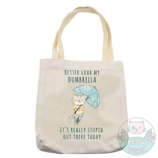 'Better grab my dumbrella - It’s really stupid out there today’ slogan with a cute kitty with (d)umbrella. Natural beige bag colour. Durable 