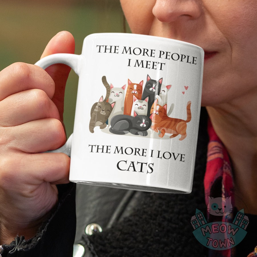 Funny The More People I Meet The More I Love Cats slogan ceramic mug, from our Meow Town Special collection. Cute kitty illustrations. Printed exclusively for You in the UK in-house by us. Funny and unique present for your cat lover friends and family. Wide range of feline themed presents for the cat lover in your life.