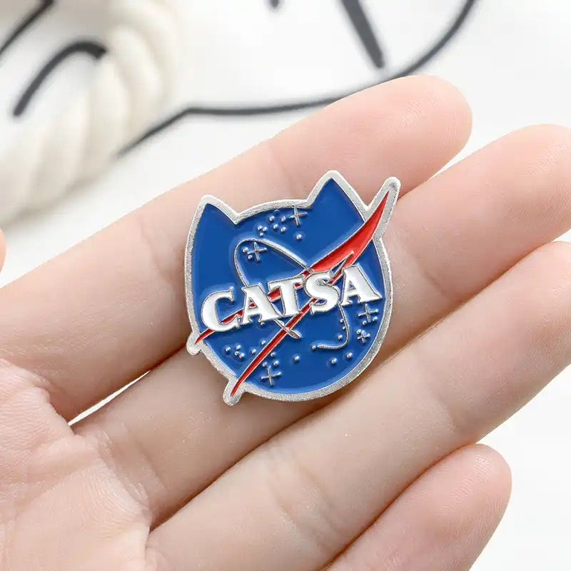 Funny NASA style ‘CATSA’ kitty shaped enamel pin badge. Gift stocking filler for cat lovers.