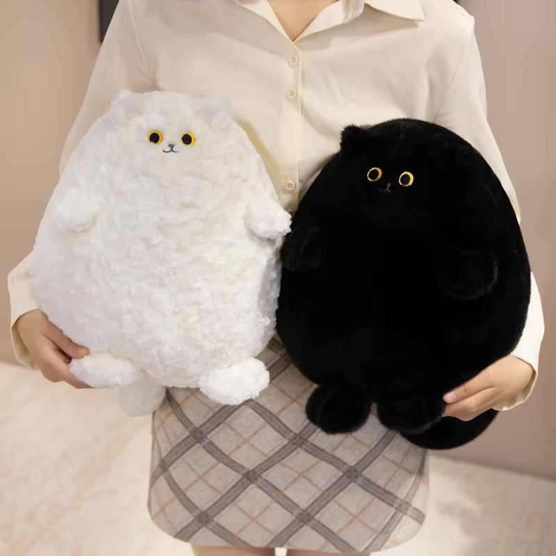 Person holding a white and a black plush cat toy against a neutral background