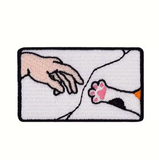 creation of the cat iron-on patch cat paw reaches for hand
