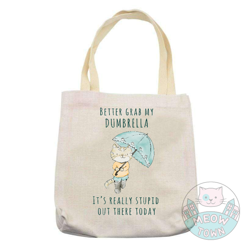'Better grab my dumbrella - It’s really stupid out there today’ slogan with a cute kitty with (d)umbrella. Natural beige bag colour. Durable 
