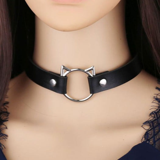 A stylish and trendy choker style necklace with kitty shaped O-ring. Black faux PU leather material, silver metalware (zinc allow). Dimensions: Full length: 39cm. Adjustable with snap fasteners in the following 3 sizes: 31.5cm, 34cm, 37cm (manual measurements, small difference might be possible). Size is suitable for teens and adults.