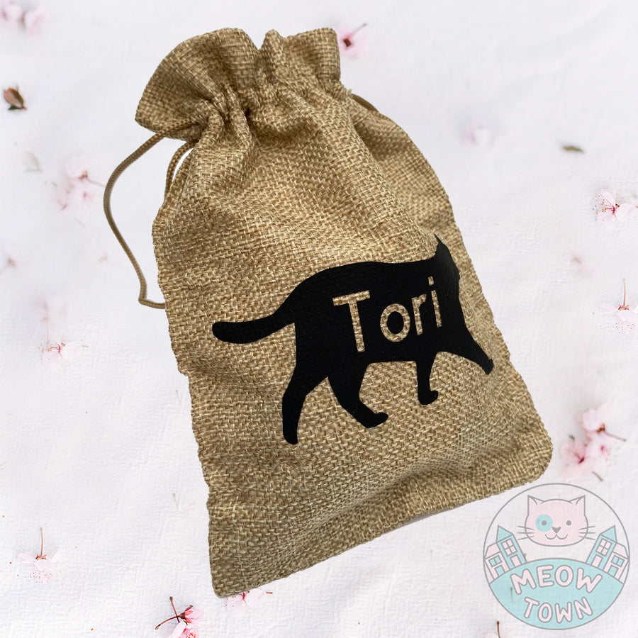 A lovely hessian/burlap bag with drawstrings for cat lovers and their furry little friends :) This cute pouch is perfect as a gift bag for any occasions such as Christmas or Birthday, or use it as a treat bag for your four-pawed friend. kitty silhouette and cut-out custom name with your pet's name.