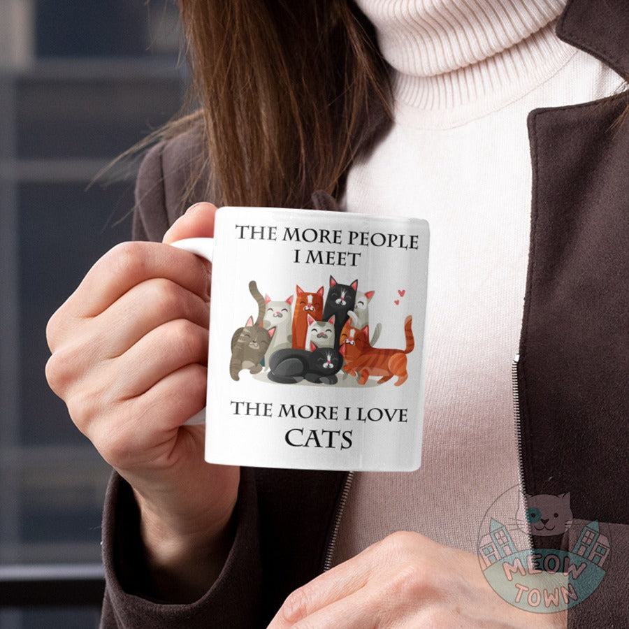 Funny The More People I Meet The More I Love Cats slogan ceramic mug, from our Meow Town Special collection. Cute kitty illustrations. Printed exclusively for You in the UK in-house by us. Funny and unique present for your cat lover friends and family.    Wide range of feline themed presents for the cat lover in your life.
