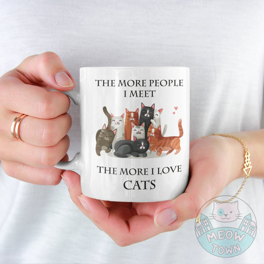 Funny The More People I Meet The More I Love Cats slogan ceramic mug, from our Meow Town Special collection. Cute kitty illustrations. Printed exclusively for You in the UK in-house by us. Funny and unique present for your cat lover friends and family.    Wide range of feline themed presents for the cat lover in your life.